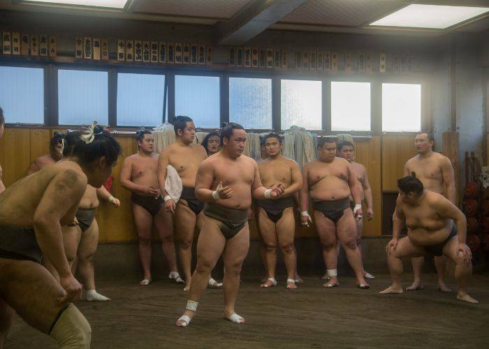 One sumo addressing a crowd of other wrestlers in the sumo stables.